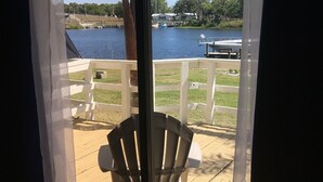 Une terrasse avec une chaise, une vue sur un lac et une clôture blanche.