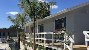 A hotel with a white exterior, a wooden deck, and a sign labeled "Office". - The Rivers Edge Motel (LaBelle)