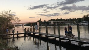A wooden pier extending into calm water with people walking and sitting. - The Rivers Edge Motel (LaBelle)