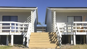 A beachfront property with two white buildings connected by a wooden staircase. - The Rivers Edge Motel (LaBelle)