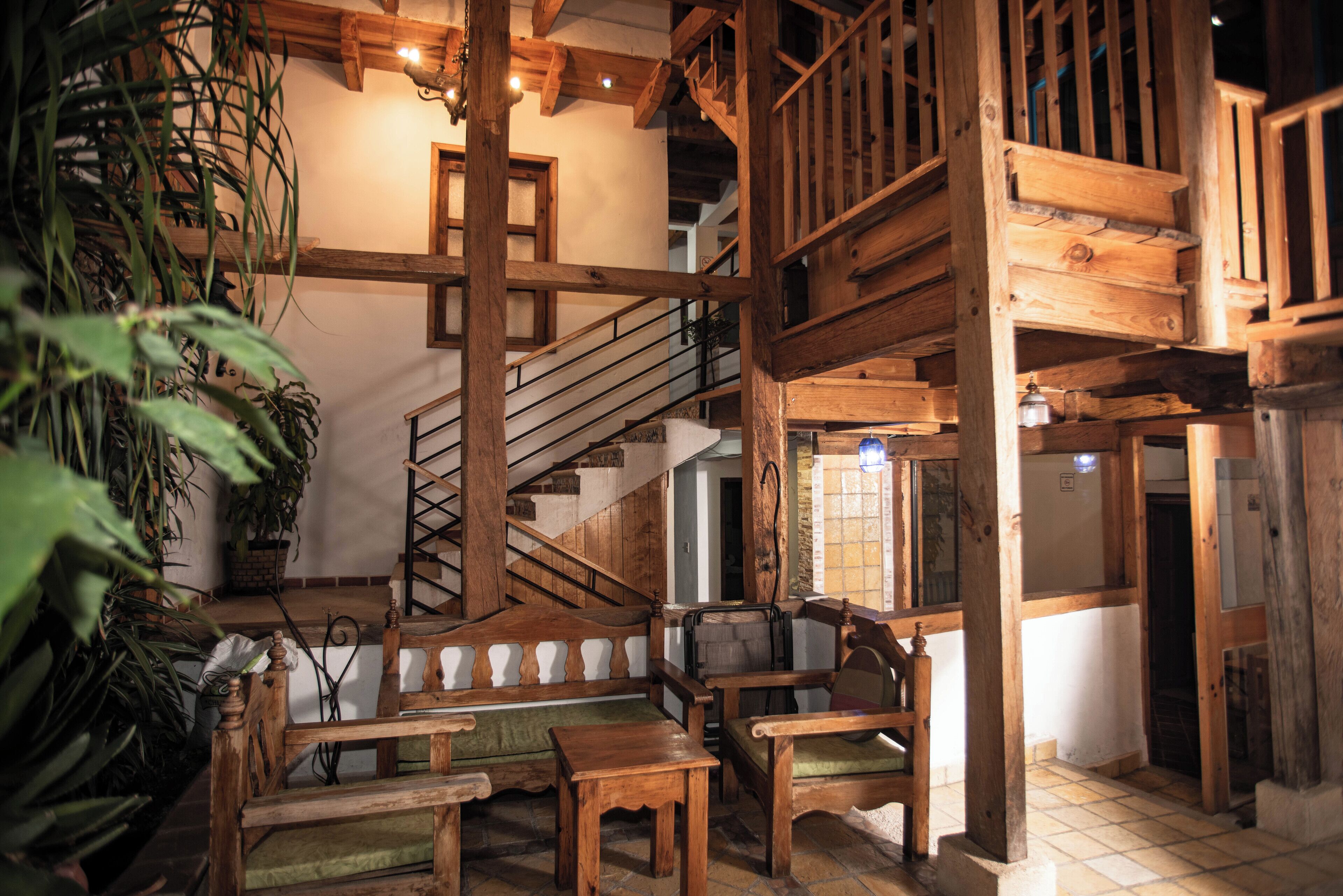 A wooden interior with a staircase, wooden furniture, and potted plants.