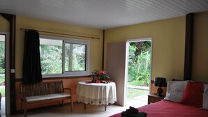 Un dormitorio con una cama, un banco, una mesa con flores y una ventana con cortinas.