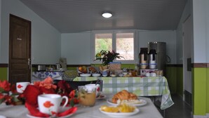 Una mesa de desayuno con diferentes alimentos, una cafetera y una ventana con vistas a zonas verdes.
