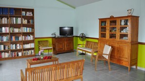 Una sala de estar con televisor, muebles de madera, una estantería y un aparador.