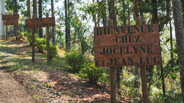 Señales de madera en un área boscosa, una de ellas con la inscripción: "Bienvenue chez Jocelyne et Jean-Luc".
