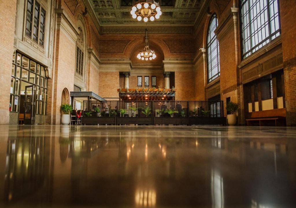 Un hall d’entrée spacieux avec un sol ciré, un espace central décoratif agrémenté de plantes et un grand lustre.