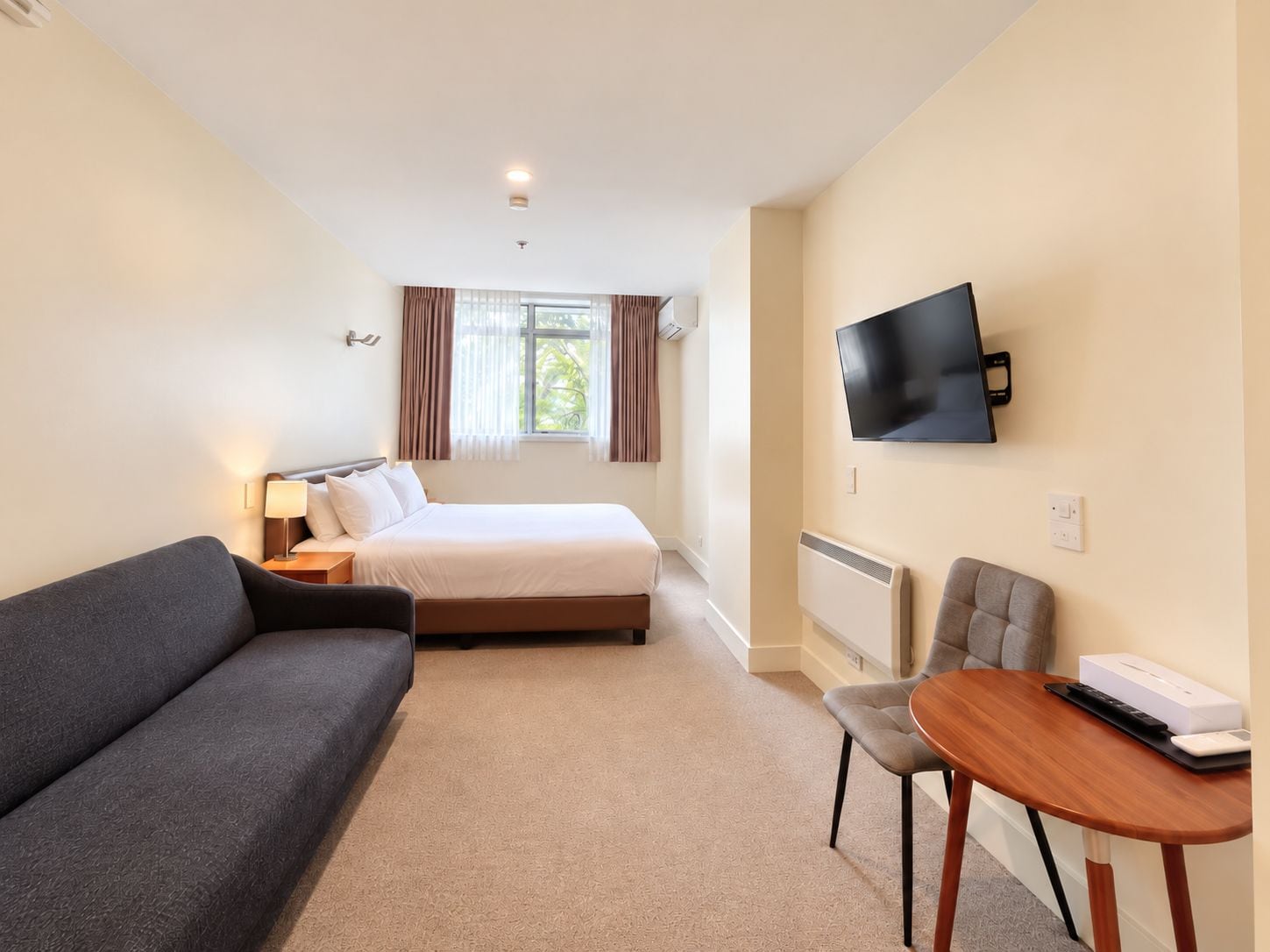 Una habitación de hotel con una cama, un sofá, un televisor y un escritorio con una silla.