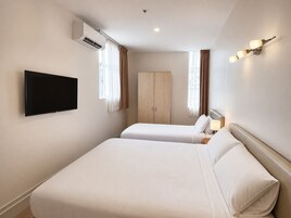 A hotel room with two beds, a flat-screen TV, an air conditioning unit, and a wardrobe.