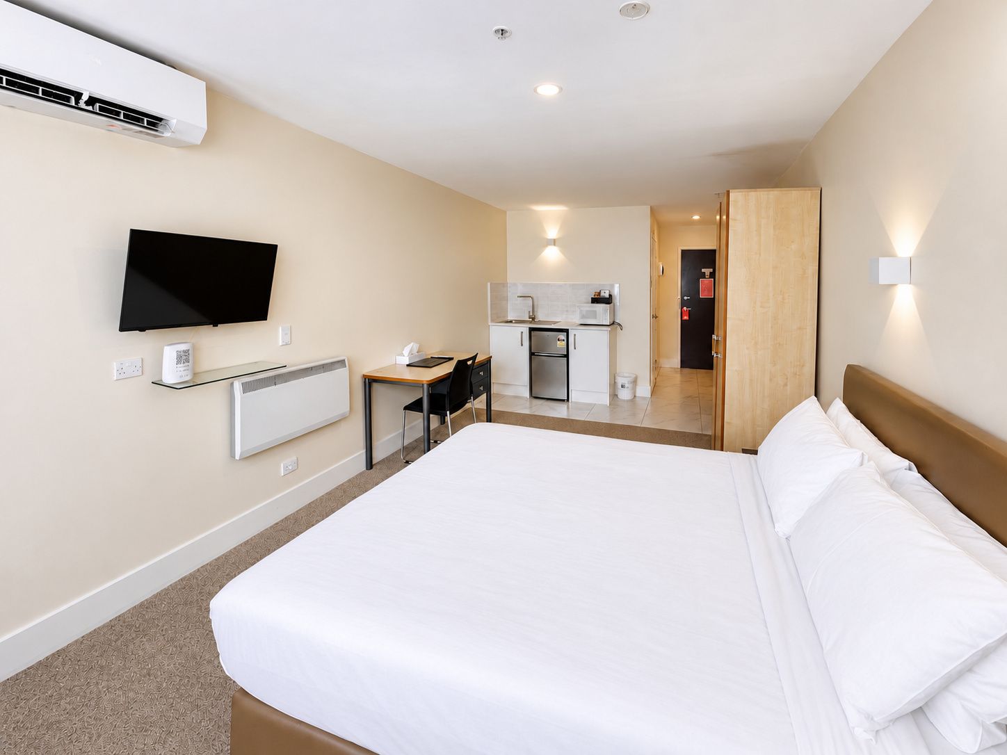 Une chambre d’hôtel comprenant un lit, un bureau, une télévision, une kitchenette et une salle de bain.