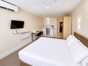 A hotel room with a bed, a desk, a television, a kitchenette, and a bathroom. - Grand Central Hotel Auckland (Auckland)