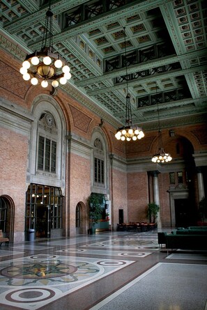 A spacious lobby with a high ceiling, ornate brick walls, and a patterned floor. - Grand Central Hotel Auckland (Auckland)