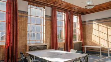 Un salón de conferencias con una amplia mesa, sillas y grandes ventanales con cortinas.