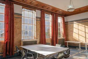 A conference room with a large table, chairs, and large windows with curtains.