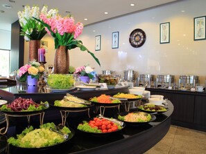 A buffet with various food items and a decorative vase with flowers.