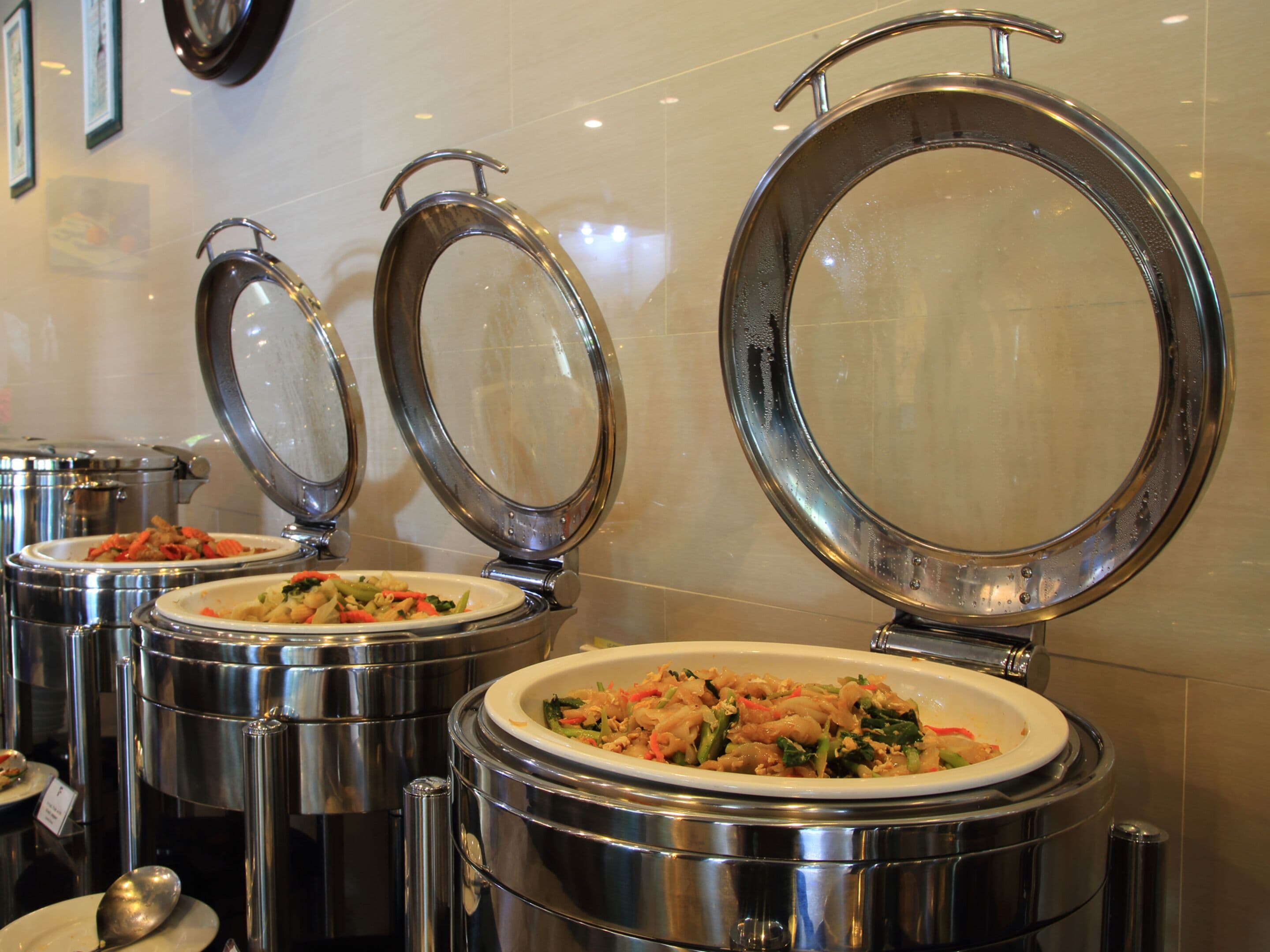 A buffet setup with multiple stainless steel serving dishes, each with a lid.