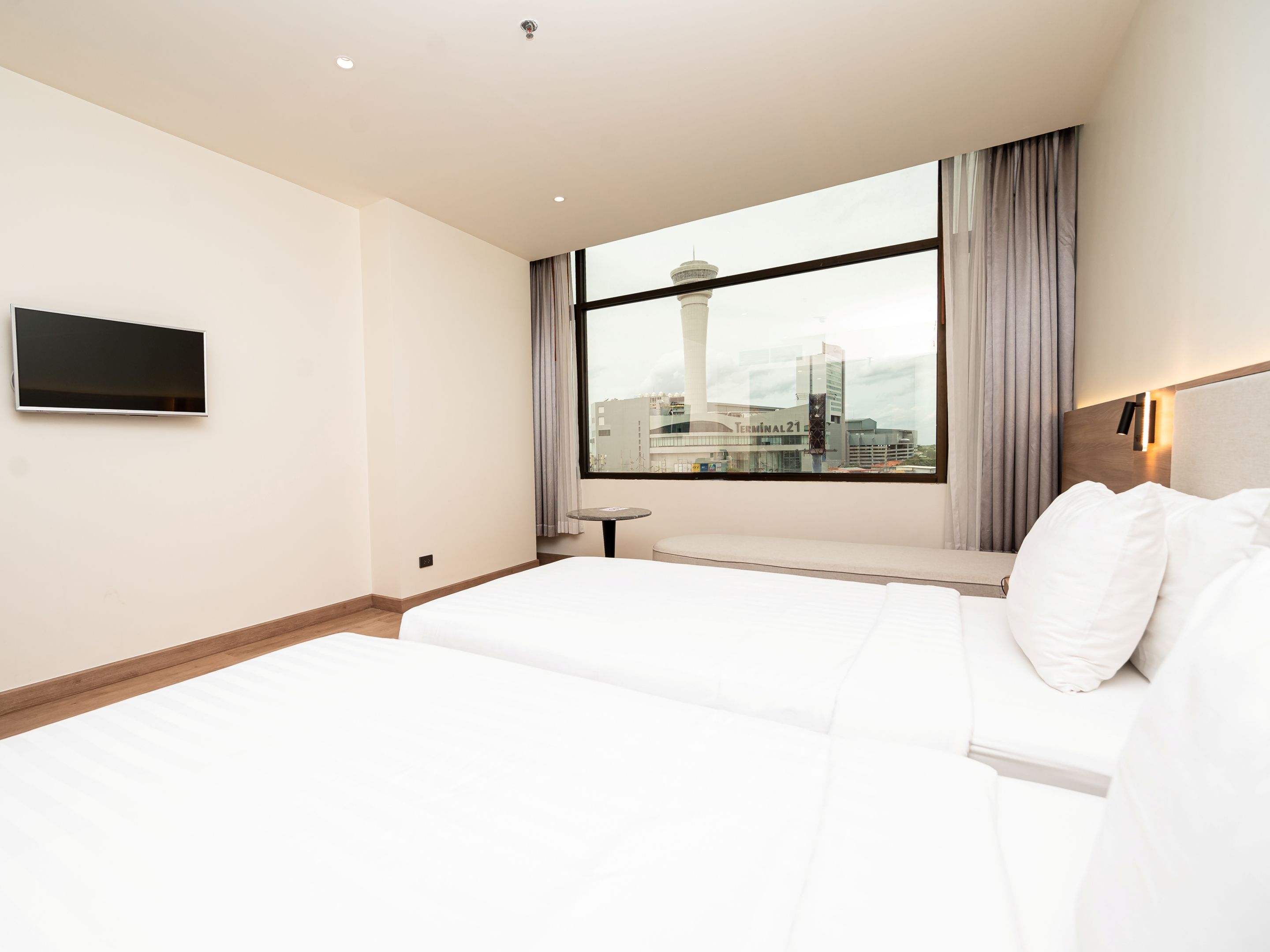 Una habitación de hotel con cama, televisión, ventana con vista a la ciudad y una pequeña mesa.
