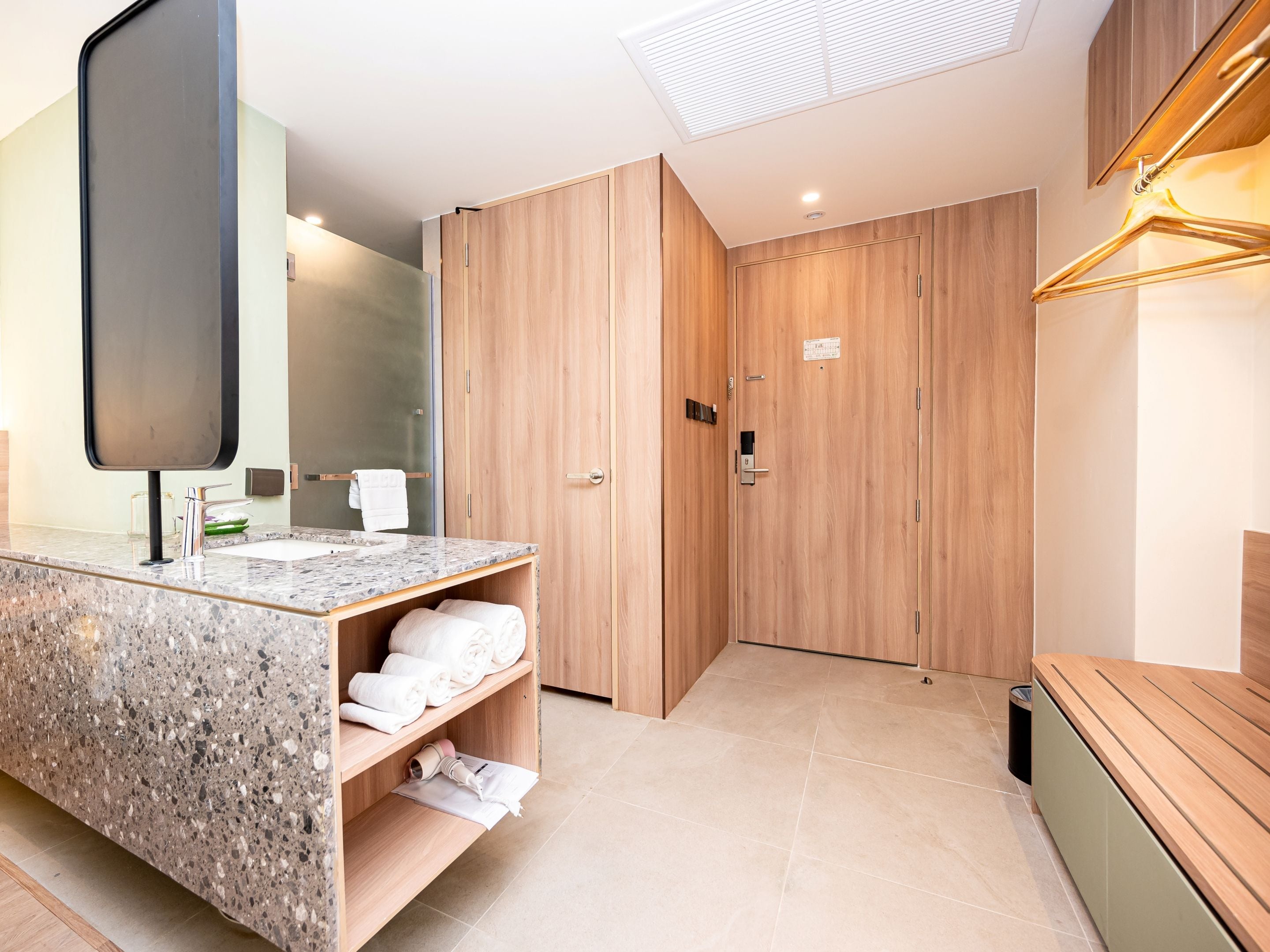 A modern bathroom with a granite countertop, wooden cabinets, and a large mirror.