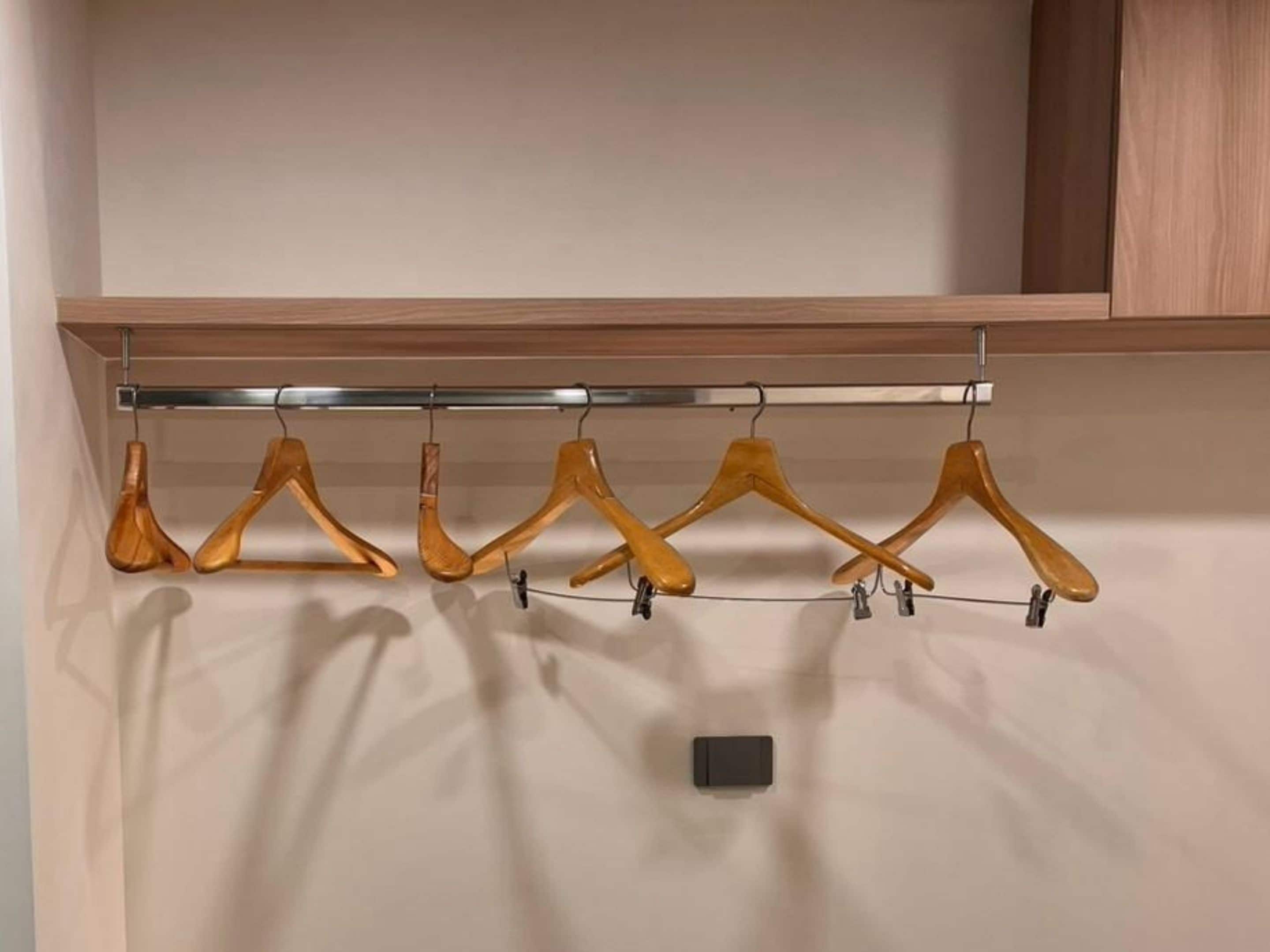 A wooden hanger rack with six hangers against a wall.