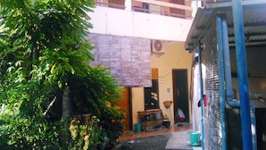 A courtyard with a small garden, a bench, and a door leading to a building. - Kost Semarang Peterongan Timur (Semarang)