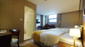 A hotel room with a bed, a desk, and a chair.