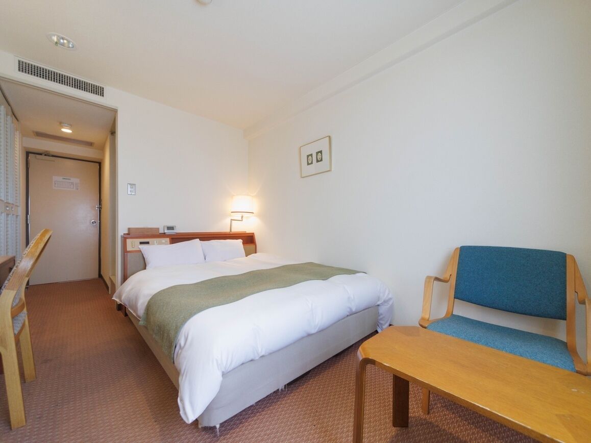 Una camera d'albergo con un letto, una scrivania, una sedia e un tavolino.