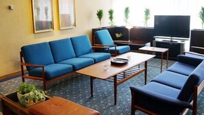 Een woonkamer met een blauwe bank, een houten salontafel en een flatscreen televisie.