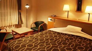 Een hotelkamer met een bed, een bureau, een stoel en twee lampen.