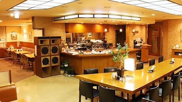 Een restaurant met een lange toonbank, meerdere zithoeken en een keuken in de achtergrond.