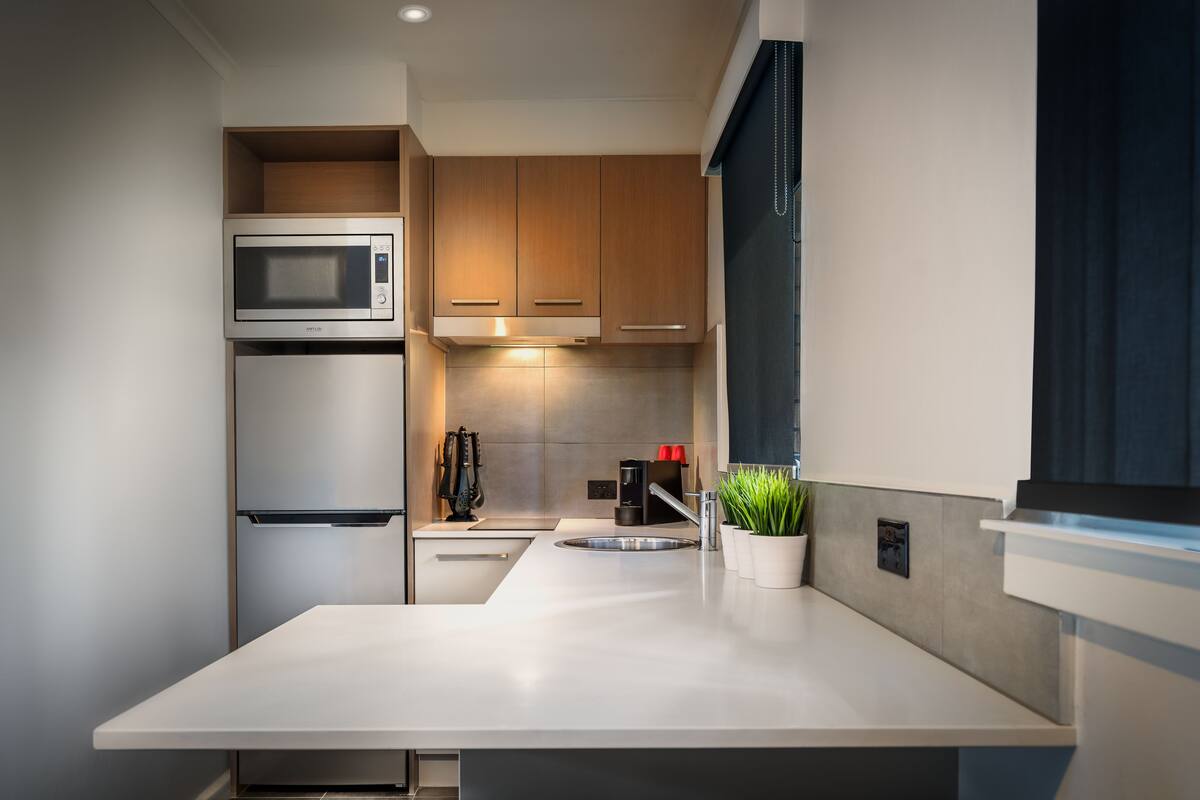 A modern kitchen with a built-in microwave, stainless steel refrigerator, and a sink.
