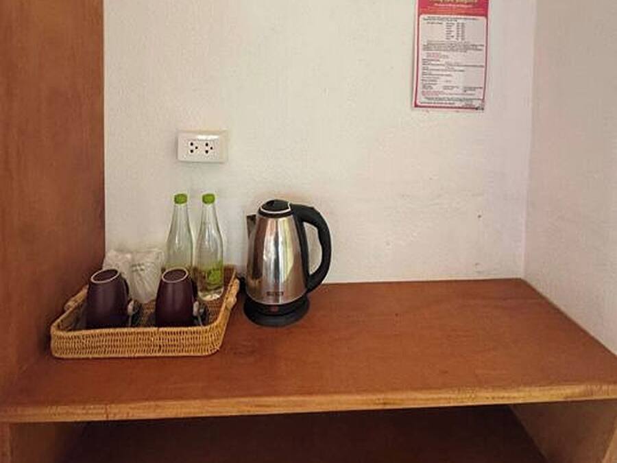 A small wooden shelf with a kettle, two bottles, and a basket containing cups.