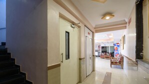 A hotel corridor with a staircase, a reception area, and a seating area. - Hotel Sai Shraddha (Rahata)