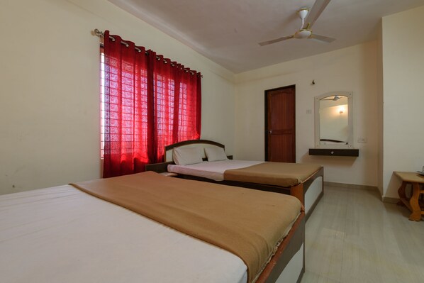 A hotel room with two beds, a ceiling fan, a mirror, and a wooden stool.