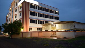 A multi-story hotel with a flat roof and a covered outdoor area. - Hotel Sai Shraddha (Rahata)