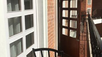 A corridor with a brick wall, white-framed windows, and a wooden door.
