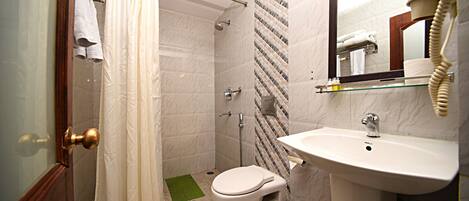 A bathroom with a shower, toilet, sink, and a mirror with a telephone.