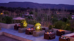 An outdoor patio with seating and tables, surrounded by planters and a view of the landscape.