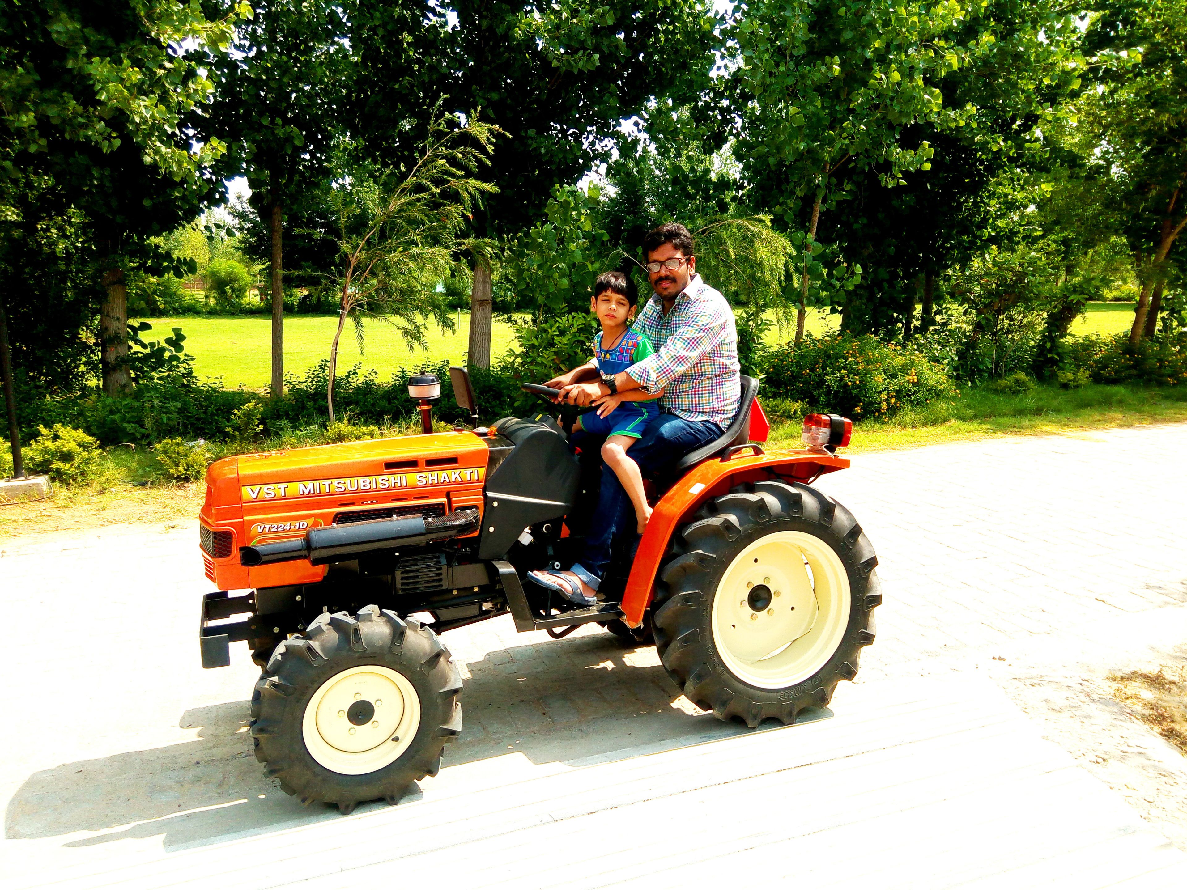 A person driving a tractor with two passengers.