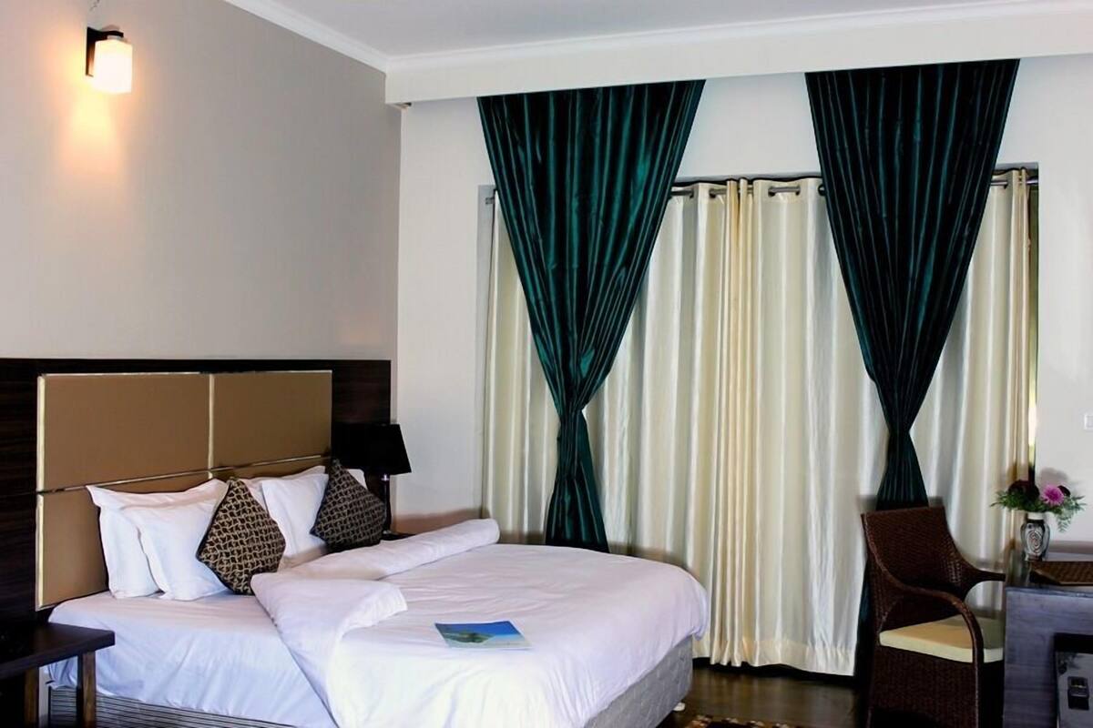 Una habitación de hotel con una cama grande, un escritorio, una silla y cortinas.
