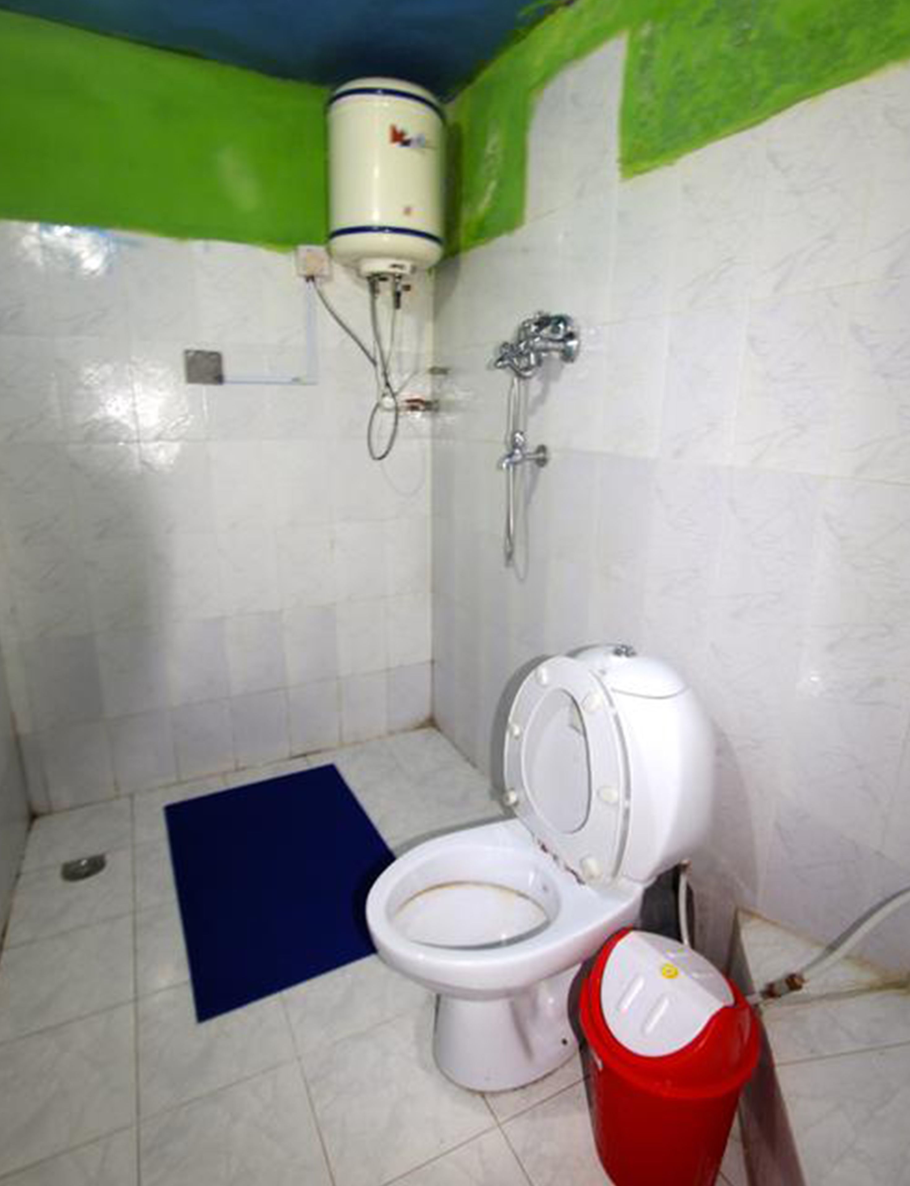 Une petite salle de bain comprenant des toilettes, une douche et un chauffe-eau.