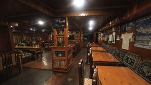 A traditional wooden interior with long tables and benches, wooden cabinets, and a variety of framed pictures on the walls. - Himalayan Lodge (Namche Bazar)