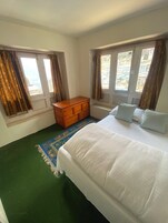 Un dormitorio con cama, cómoda de madera y ventana con cortinas.