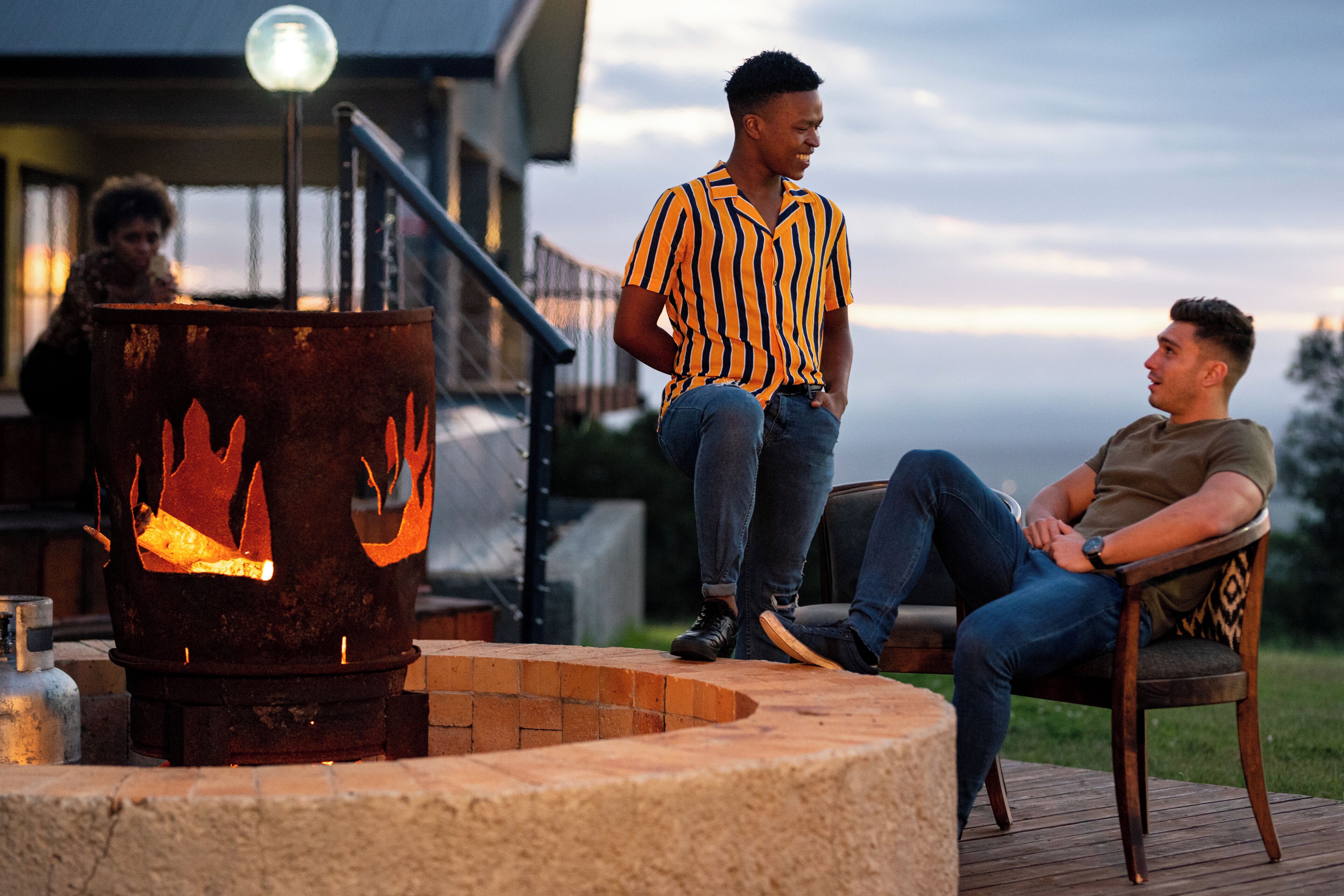A patio area with a fire pit, outdoor seating, and a view of a building in the background.