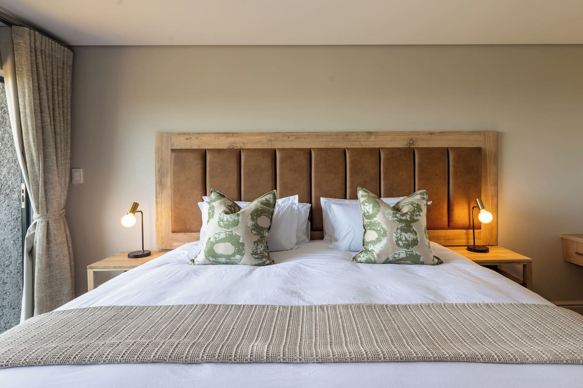 A neatly made bed with a wooden headboard, two bedside lamps, and a decorative pillow.