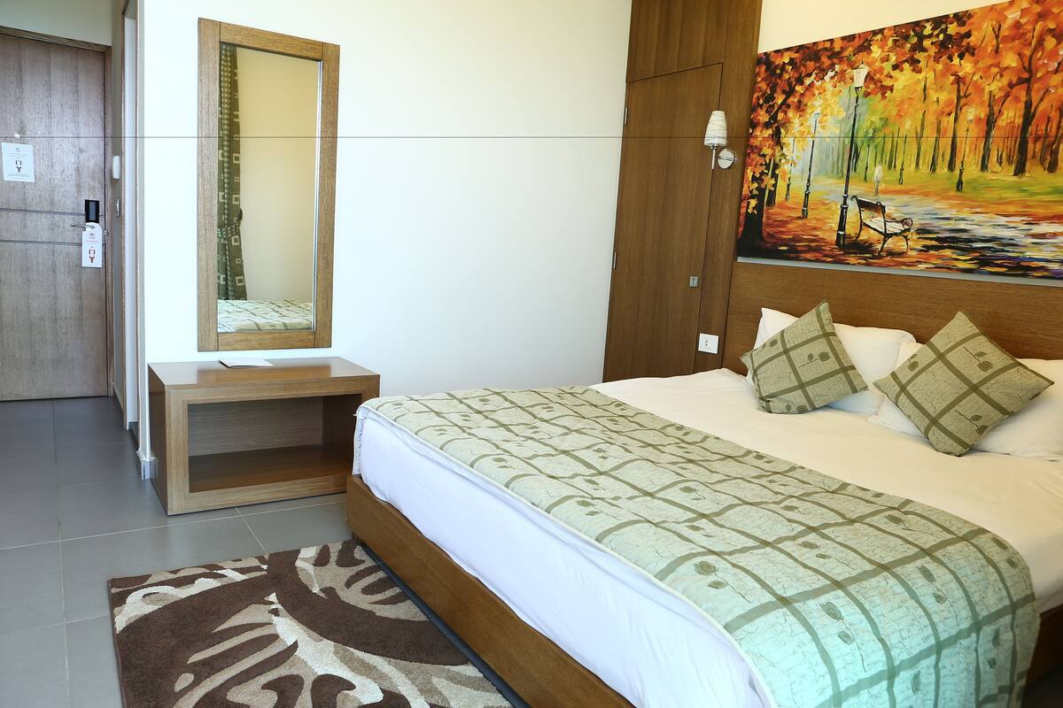 Un dormitorio con cama, mesita de noche, espejo, cuadro y armario.