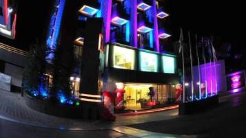A multi-story hotel with a modern design, featuring illuminated windows and a prominent logo.
