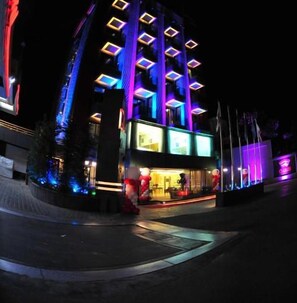 A multi-story hotel with a modern design, featuring illuminated windows and a prominent logo. - Guias Boutique Hotel & SPA (Qartaboun)