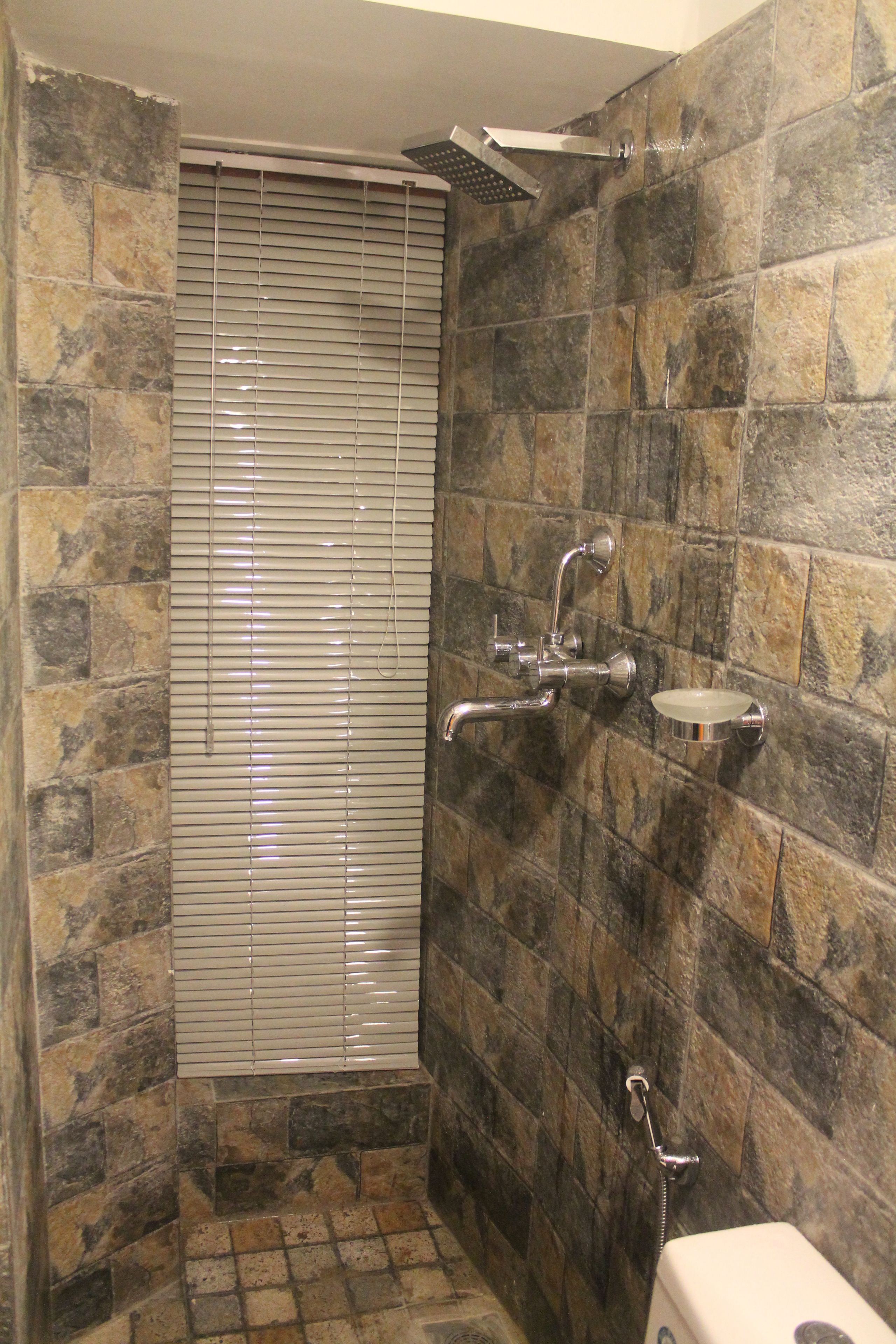 A bathroom with stone walls, a shower, and a toilet.