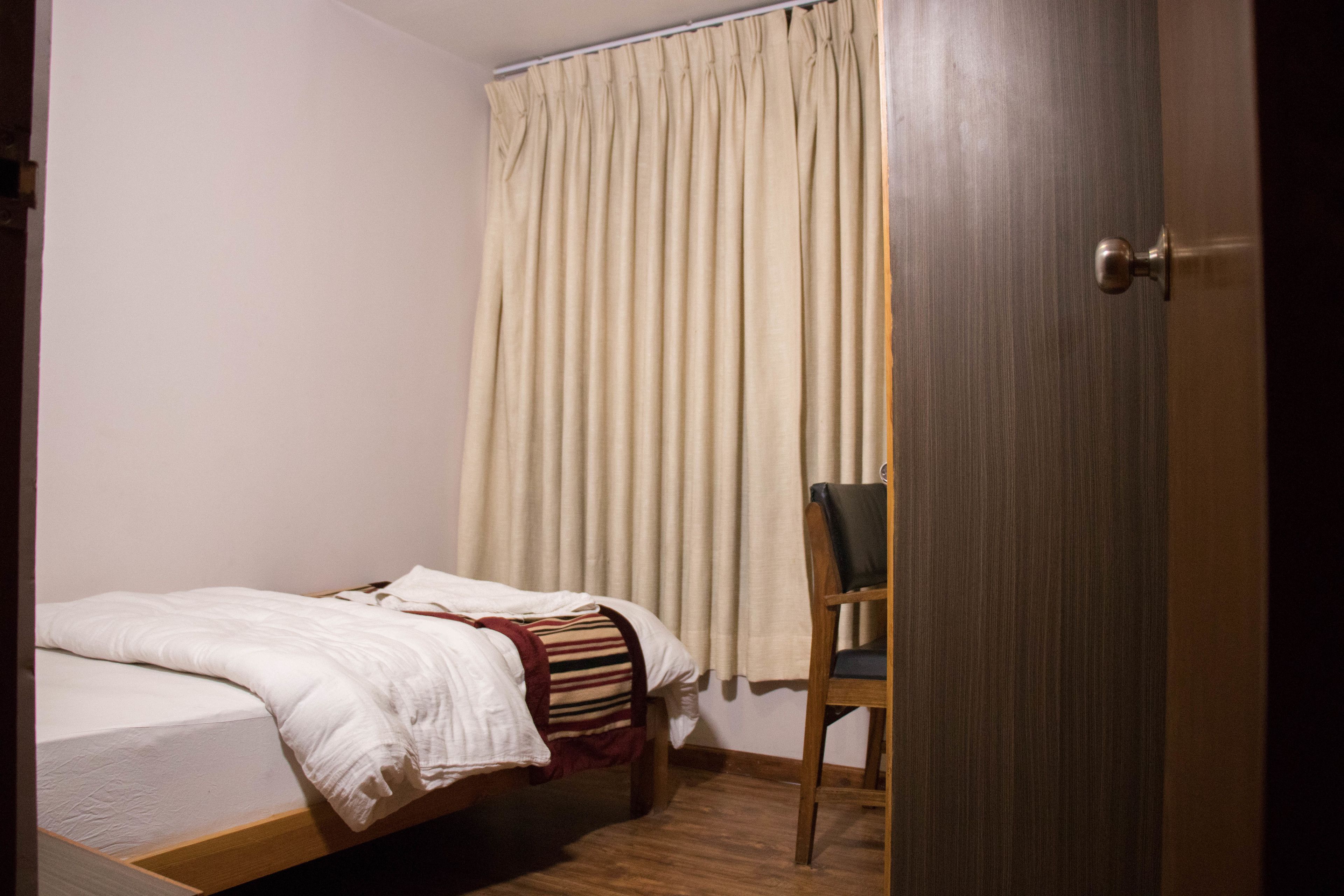 A bedroom with a bed, a chair, and a door.
