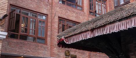 Un edificio de ladrillo de varios pisos con fachada tradicional, con varias ventanas y un letrero que indica que se trata de un negocio.