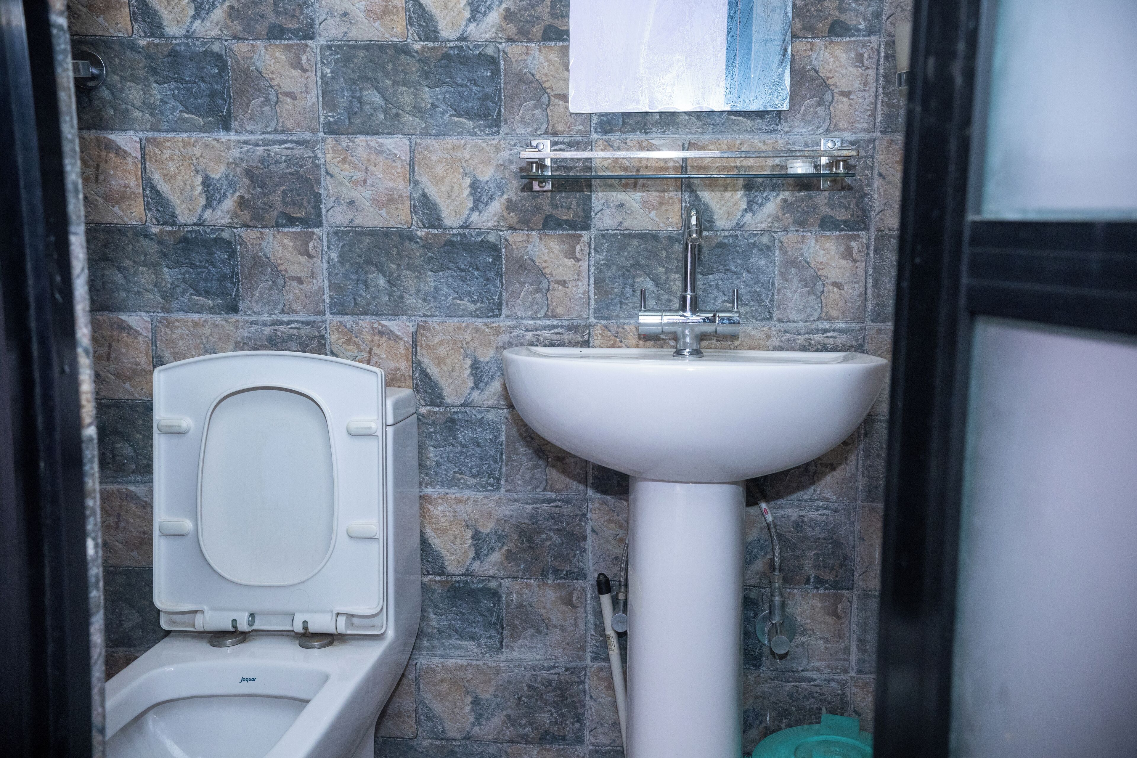 Une salle de bain avec des toilettes, un lavabo et des murs carrelés.